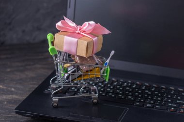 Dizüstü bilgisayar klavyesindeki alışveriş sepetinde günlük alışveriş ler ve hediyeler. Çevrimiçi mağazalarda alışveriş