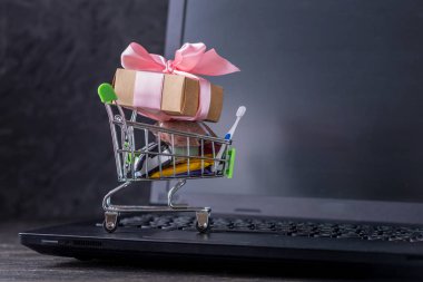 Dizüstü bilgisayar klavyesindeki alışveriş sepetinde günlük alışveriş ler ve hediyeler. Çevrimiçi mağazalarda alışveriş