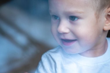 Sevimli bebek bebek yansıma ile pencere cam bakıyor. Çocukların yalnızlığı. Yetimhane ve yetimler