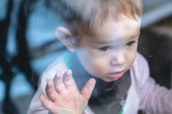 Cute Baby Boy patrząc w szkło okienne z odbicia. Samotność dzieci i czekanie na życzliwość. — Zdjęcie stockowe