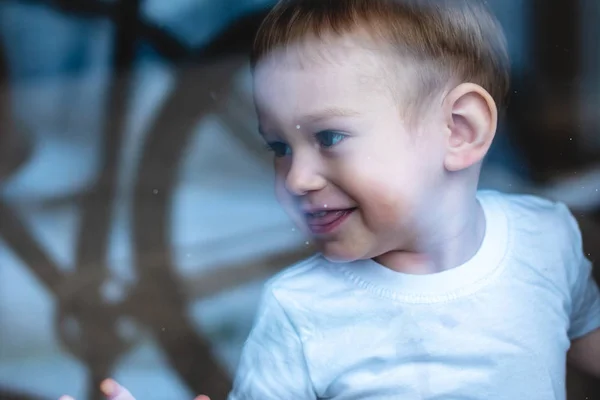 Bébé garçon mignon regardant dans la vitre avec réflexion. La solitude des enfants. Orphelinat et orphelins — Photo