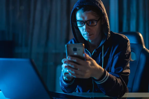 Ein männlicher Hacker unter der Haube, der das Telefon in der Hand hält und versucht, mit Passwörtern Zugang zu Datenbanken zu stehlen. Cybersicherheit — Stockfoto