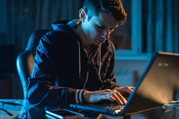 Młody człowiek pracownik pracujący na laptopie w nocy. Projektant Freelancer lub administrator systemu pozostał późno w pracy. — Zdjęcie stockowe