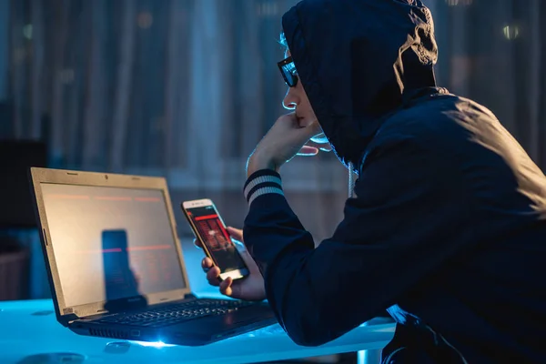 Access veritabanları parolalarla çalmaya çalışan onun elinde telefon tutarak Hood erkek hacker. Cybersecurity