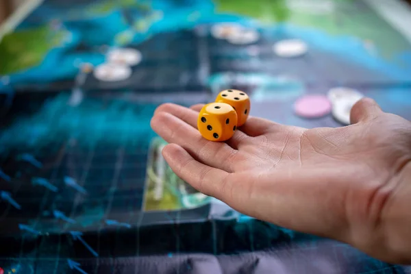 Hand wirft gelbe Würfel auf das Spielfeld. Glück und Aufregung. Brettspiele. Spielmomente in Dynamik — Stockfoto