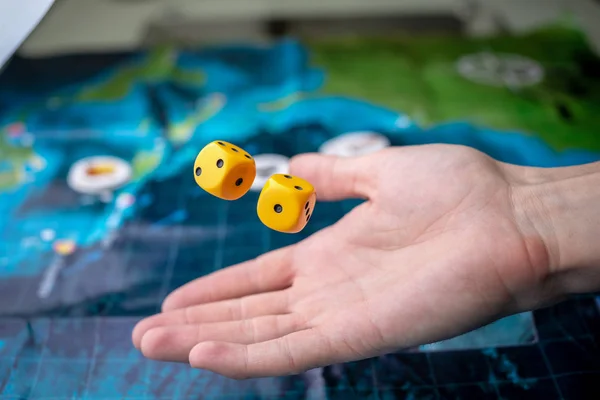 De hand gooit geel dobbelstenen op het speelveld. Geluk en opwinding. Concept-bordspellen — Stockfoto