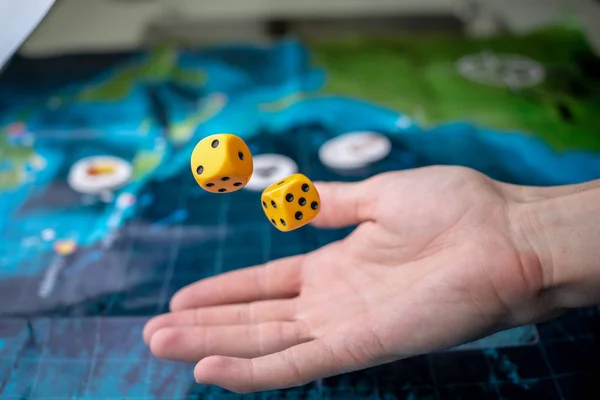 Hand throws yellow dice on the playing field. Luck and excitement. Concept of Board games. Gaming moments in dynamics