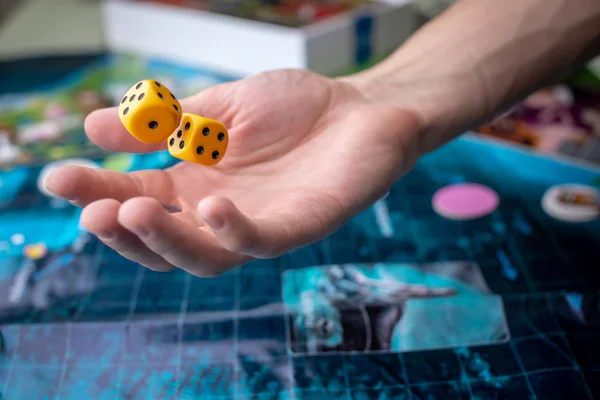 Hand wirft zwei gelbe Würfel auf das Spielfeld. Glück und Aufregung. Brettspiele. Spielmomente in Dynamik — Stockfoto