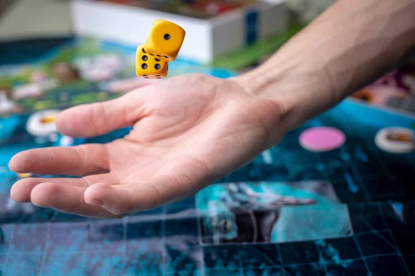 The hand throws yellow dice on the playing field. Luck and excitement. Concept Board games