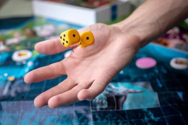 Hand wirft gelbe Würfel auf das Spielfeld. Glück und Aufregung. Brettspiele. Spielmomente in Dynamik — Stockfoto