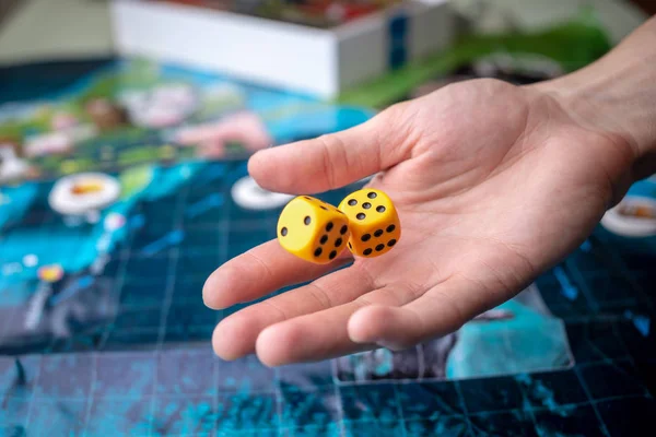 Wirft die Hand gelbe Würfel auf das Spielfeld. Glück und Aufregung. Konzept Brettspiele — Stockfoto