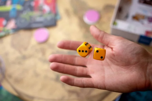 La mano lanza dos dados amarillos en el campo de juego. El concepto de juegos de mesa. Momentos de juego en la dinámica — Foto de Stock