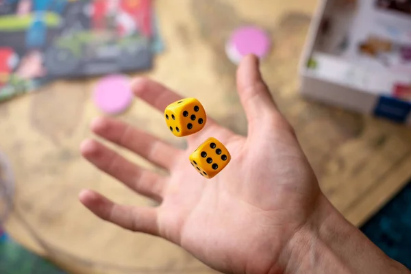 Hand wirft gelbe Würfel auf das Spielfeld. Glück und Aufregung. Konzept der Brettspiele. Spielmomente in Dynamik — Stockfoto