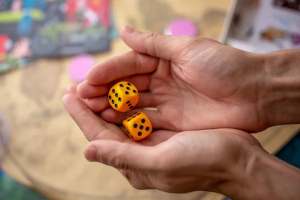 Hände werfen gelbe Würfel auf das Spielfeld. Glück und Aufregung. Konzept der Brettspiele. Spielmomente in Dynamik — Stockfoto