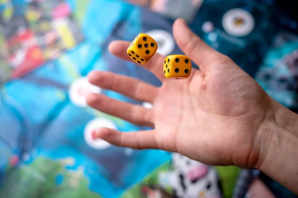 Wirft die Hand zwei gelbe Würfel auf das Spielfeld. das Konzept der Brettspiele. Spielmomente in Dynamik — Stockfoto