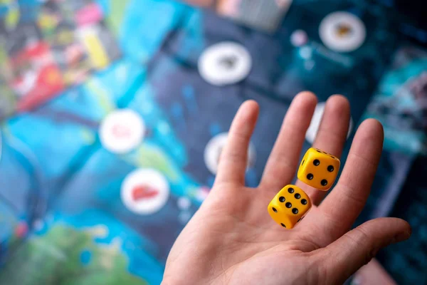 Hand wirft zwei gelbe Würfel auf das Spielfeld. Spielmomente in Dynamik. Glück und Aufregung. Brettspielstrategie — Stockfoto