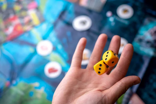Wirft die Hand zwei gelbe Würfel auf das Spielfeld. Spielmomente in Dynamik. Konzept Brettspiele Strategie — Stockfoto