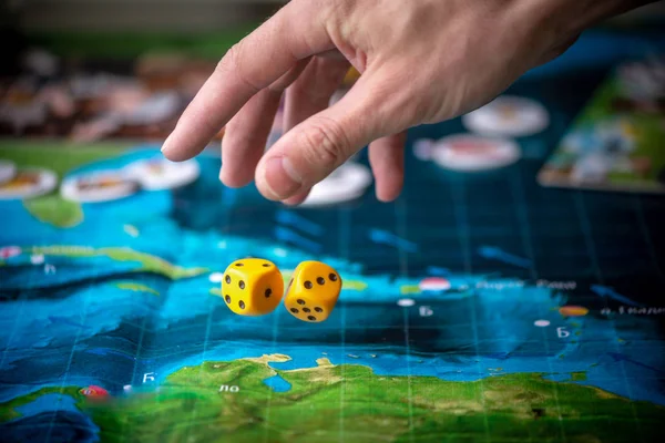 Hand throws two yellow dice on the playing field. Gaming moments in dynamics. Luck and excitement. Board games strategy — Stock Photo, Image