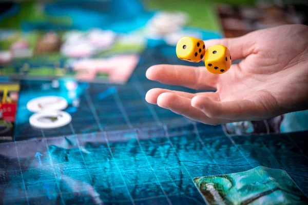 Wirft die Hand zwei gelbe Würfel auf das blaue Spielfeld. Spielmomente in Dynamik. Konzept Brettspiele Strategie — Stockfoto