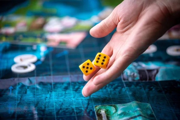 Hand wirft zwei gelbe Würfel auf das blaue Spielfeld. Spielmomente in Dynamik. Glück und Aufregung. Brettspiele — Stockfoto