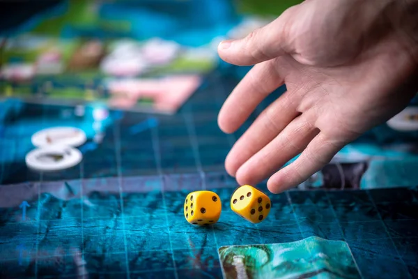 Hand wirft zwei gelbe Würfel auf das blaue Feld des Fantasy-Spiels. Spielmomente in Dynamik. Brettspielstrategie — Stockfoto
