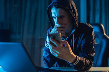 Access veritabanları parolalarla çalmaya çalışan onun elinde telefon tutarak Hood erkek hacker. Cybersecurity