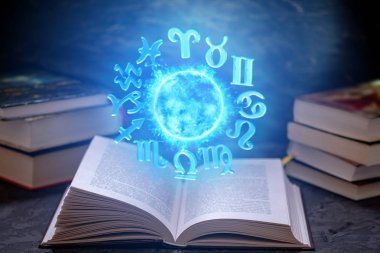 Astroloji karanlık bir arka plan üzerine açık kitap. Büyülü küre mavi ışık zodyak işaretleri ile parlayan.