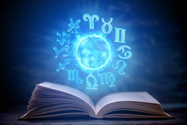 Astroloji karanlık bir arka plan üzerine açık kitap. Büyülü küre mavi ışık zodyak işaretleri ile parlayan.