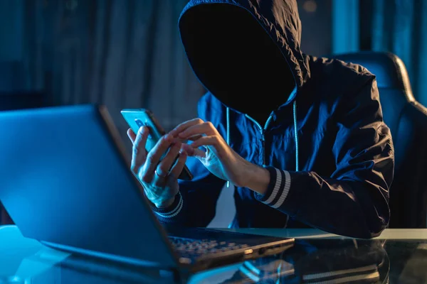 Programador de hackers anônimo usa um laptop para hackear o sistema no escuro. Conceito de cibercrime e base de dados de pirataria — Fotografia de Stock