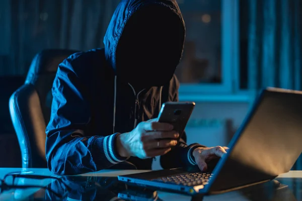 Anonymous hacker programmer uses a laptop to hack the system in the dark. Concept of cybercrime and hacking database — Stock Photo, Image