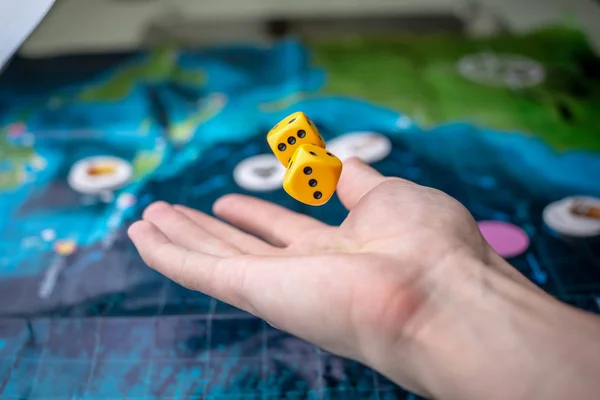 Hand wirft gelbe Würfel auf das Spielfeld. Glück und Aufregung. Konzept der Brettspiele. Spielmomente in Dynamik — Stockfoto