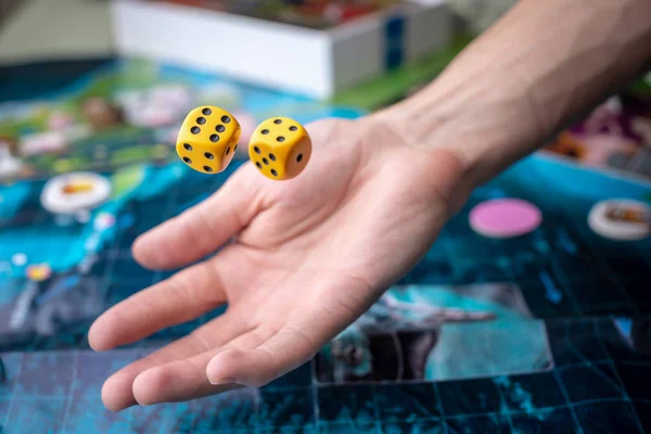 Hand wirft gelbe Würfel auf das Spielfeld. Glück und Aufregung. Konzept der Brettspiele. Spielmomente in Dynamik — Stockfoto