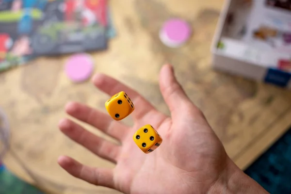 The hand throws yellow dice on the playing field. Luck and excitement. Concept Board games