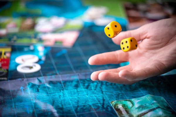 Wirft die Hand zwei gelbe Würfel auf das blaue Spielfeld. Spielmomente in Dynamik. Konzept Brettspiele Strategie — Stockfoto