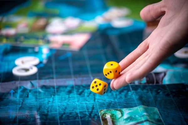 Hand wirft zwei gelbe Würfel auf das blaue Feld des Fantasy-Spiels. Spielmomente in Dynamik. Brettspielstrategie — Stockfoto