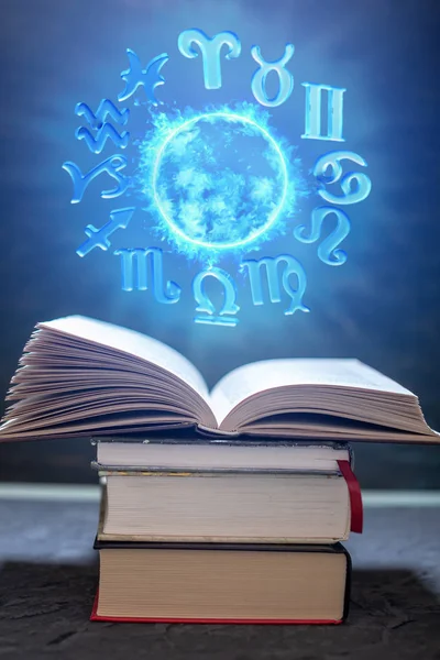 Open boek over astrologie op een donkere achtergrond. De gloeiende magische wereld met tekens van de dierenriem in het blauwe licht — Stockfoto