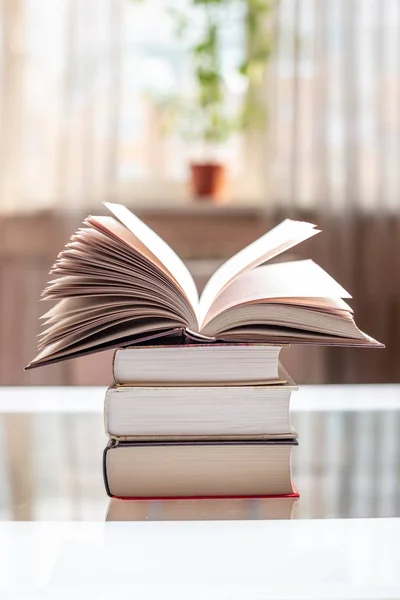 Nyitott könyv egy halom könyvet, egy asztal, egy világos szobában. Oktatás és olvasó könyv könyvek — Stock Fotó
