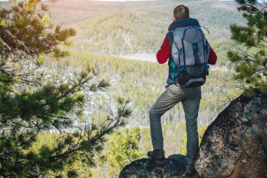 Büyük bir sırt çantası ile Adam turist bir kaya lık üzerinde duruyor ve yayılan yeşil vadi bakıyor. Seyahatte özgürlük