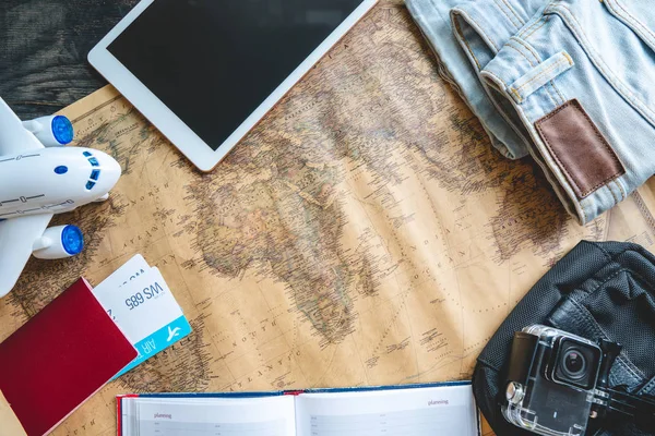 Passagens aéreas, passaporte, câmera, tablet, jeans e mapa na mesa. Reunião para uma viagem ou viagem para conhecer aventuras . — Fotografia de Stock