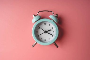 Şık pembe arka planda mavi analog metal çalar saat. Pastel renklerde zaman kavramı