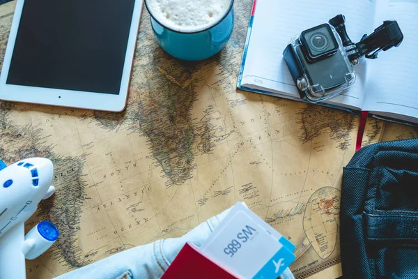 航空券、パスポート、カメラ、タブレット、ジーンズ、テーブルの上の地図。冒険を満たすために旅行や旅行のための集まり. — ストック写真