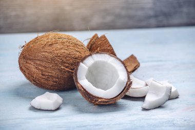 Mavi ahşap arka plan üzerinde beyaz hamuru ile açık hindistan cevizi. Kozmetikte yaygın olarak kullanılan organik sağlıklı vegan ürün