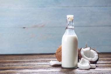 Ahşap bir arka plan üzerinde beyaz et ile bir şişe hindistan cevizi sütü. Kozmetolojide kullanılan organik sağlıklı ürün