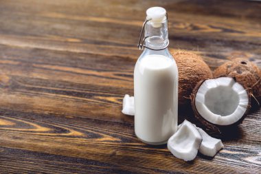 Ahşap bir arka plan üzerinde beyaz et ile bir şişe hindistan cevizi sütü. Kozmetolojide kullanılan organik sağlıklı ürün