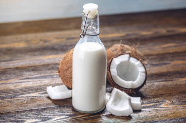 Ahşap bir arka plan üzerinde beyaz et ile bir şişe hindistan cevizi sütü. Kozmetolojide kullanılan organik sağlıklı ürün