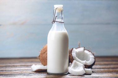 Mavi ahşap arka plan üzerinde beyaz et ile bir şişe hindistan cevizi sütü. Kozmetolojide kullanılan organik sağlıklı ürün