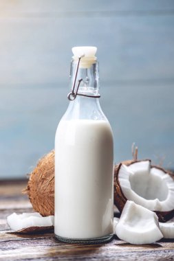 Mavi ahşap arka plan üzerinde beyaz et ile bir şişe hindistan cevizi sütü. Kozmetolojide kullanılan organik sağlıklı ürün