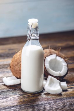 Ahşap bir arka plan üzerinde beyaz et ile bir şişe hindistan cevizi sütü. Kozmetolojide kullanılan organik sağlıklı ürün
