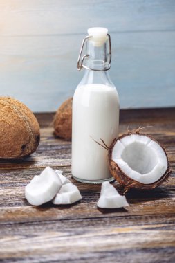 Ahşap bir arka plan üzerinde beyaz et ile bir şişe hindistan cevizi sütü. Kozmetolojide kullanılan organik sağlıklı ürün
