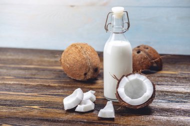 Ahşap bir arka plan üzerinde beyaz et ile bir şişe hindistan cevizi sütü. Kozmetolojide kullanılan organik sağlıklı ürün